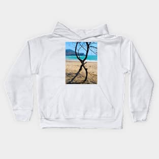 Vertical view through two curved pine tree trunks to a sand beach Kids Hoodie